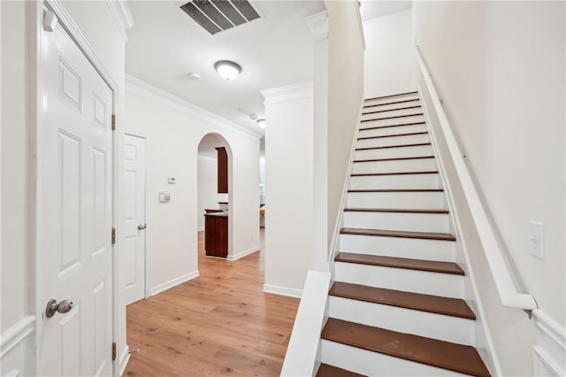 stairway with wood-type flooring and ornamental molding