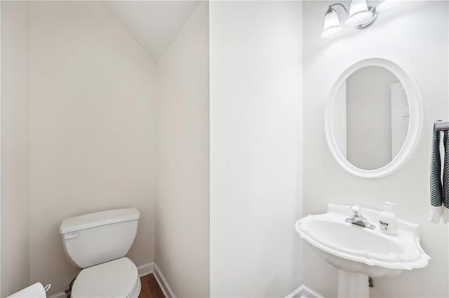 bathroom with vaulted ceiling, sink, and toilet