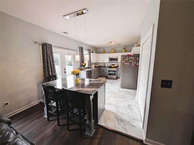 640 Dahoma Trl, Woodstock, GA 30188 - kitchen with appliances with stainless steel finishes, a textured ceiling, white cabinets, pendant lighting, and light marble finish floors