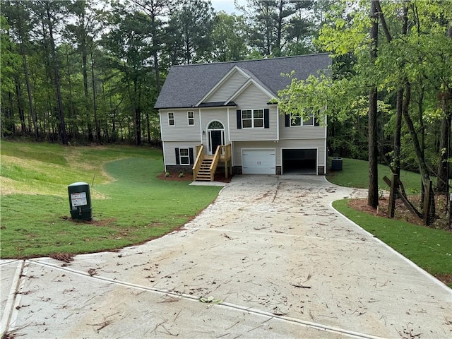 split foyer home featuring concrete driveway, an attached garage, a front lawn, and cooling unit