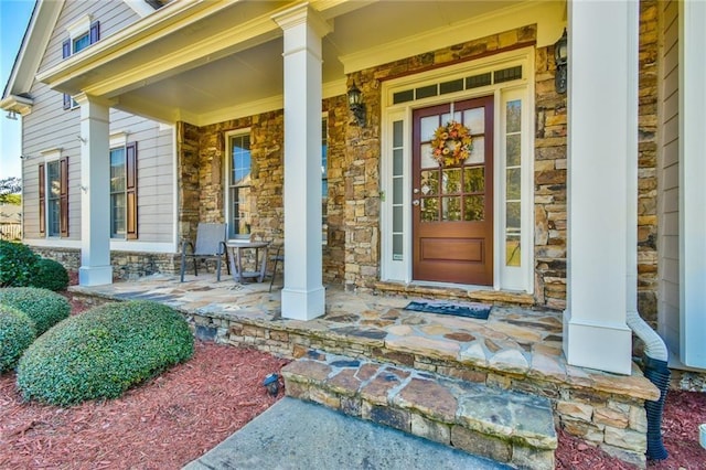 view of exterior entry featuring stone siding and a porch