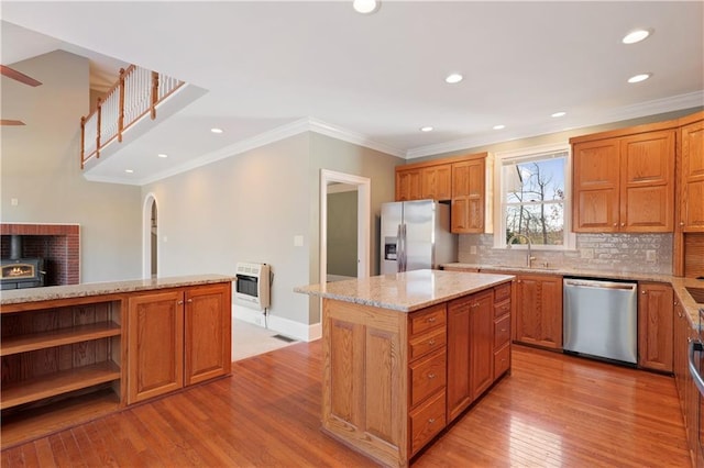 kitchen with light stone counters, backsplash, light hardwood / wood-style floors, stainless steel appliances, and a center island