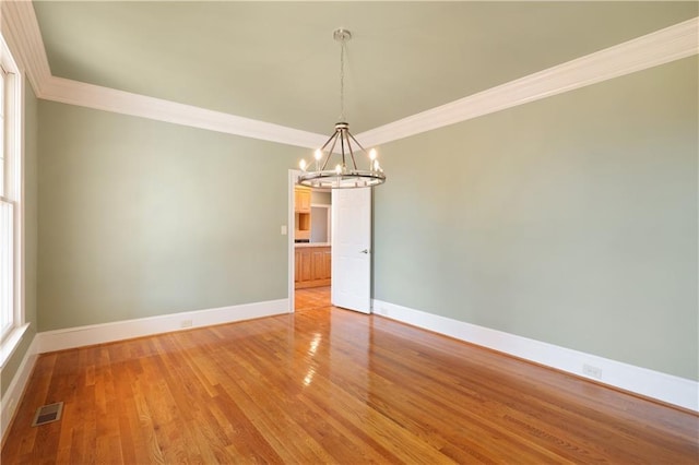 unfurnished room featuring crown molding, light wood-type flooring, and an inviting chandelier