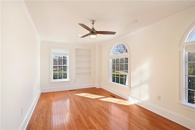 spare room with ceiling fan, a wealth of natural light, and light wood-type flooring