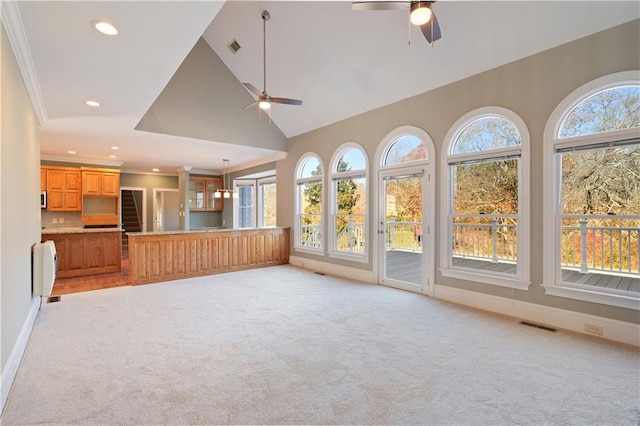 unfurnished living room featuring light colored carpet, ceiling fan, high vaulted ceiling, and crown molding