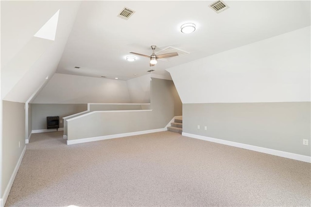 bonus room with light colored carpet, vaulted ceiling with skylight, and ceiling fan