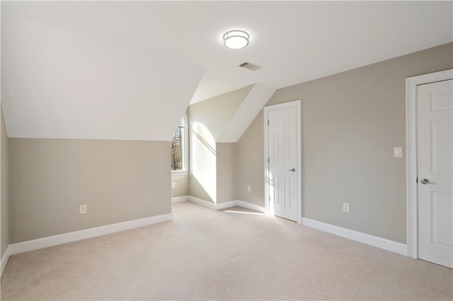 additional living space featuring lofted ceiling and light colored carpet