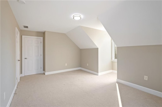 bonus room with lofted ceiling and light colored carpet