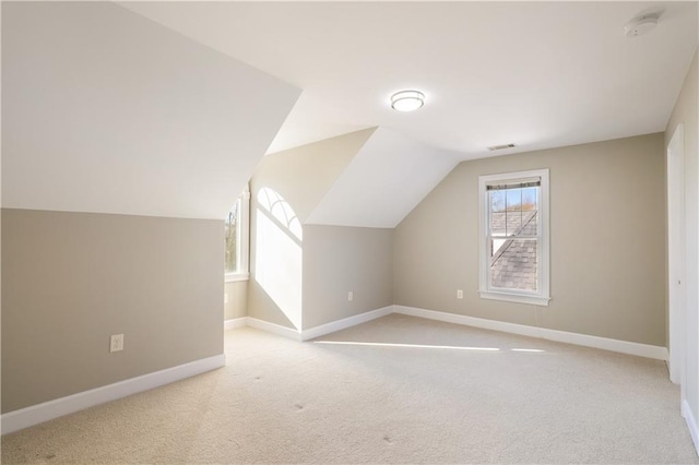 additional living space featuring lofted ceiling and light colored carpet