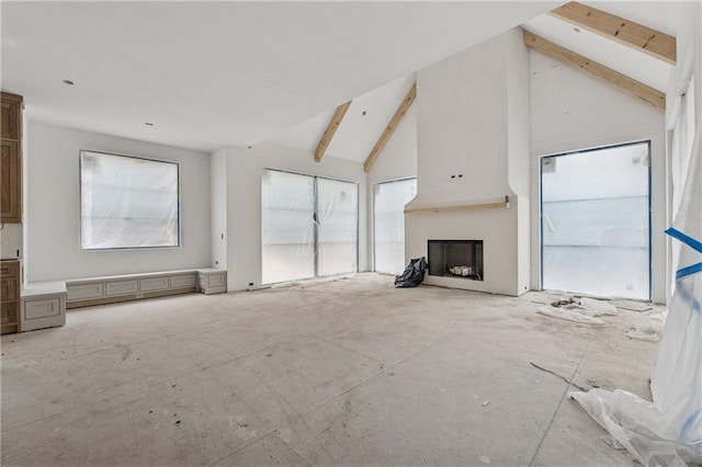 unfurnished living room with vaulted ceiling with beams and a fireplace