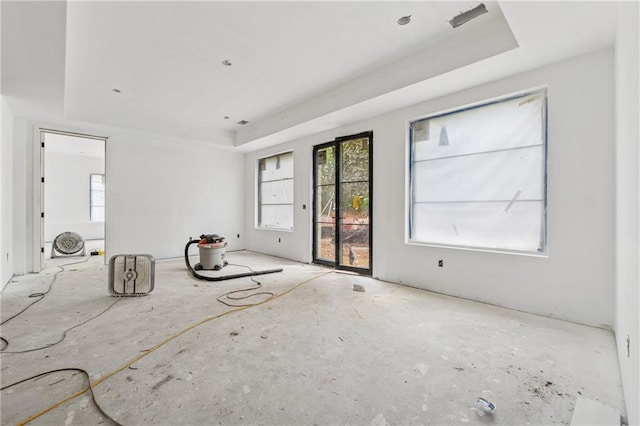 unfurnished living room with plenty of natural light and a tray ceiling
