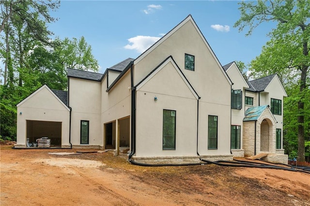exterior space featuring a garage, stucco siding, and a shingled roof
