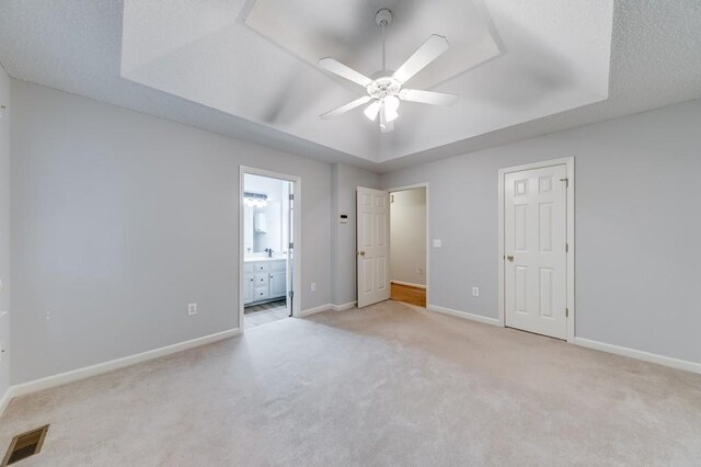 215 Twin Creek Shrs, Athens, GA 30605 - unfurnished bedroom featuring a tray ceiling, light carpet, connected bathroom, and a ceiling fan