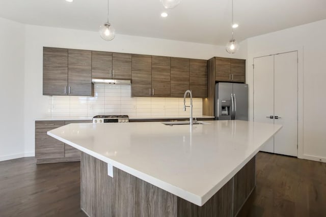 kitchen with a kitchen island with sink, dark hardwood / wood-style flooring, stainless steel appliances, and an inviting chandelier