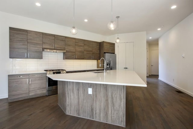 kitchen featuring appliances with stainless steel finishes, dark hardwood / wood-style flooring, a kitchen island with sink, and sink