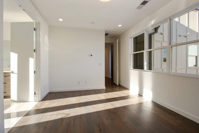 unfurnished bedroom featuring ensuite bathroom, dark hardwood / wood-style floors, a closet, and multiple windows