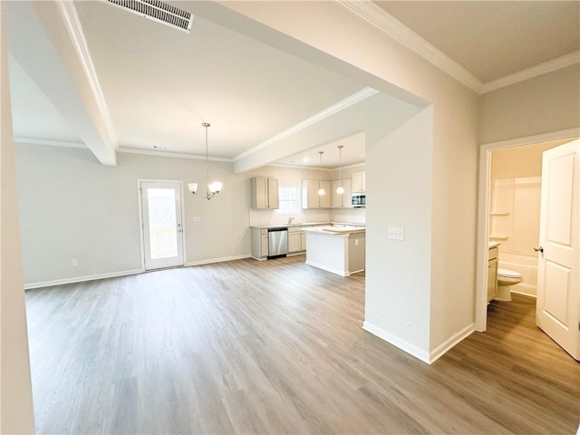 unfurnished living room featuring baseboards, a notable chandelier, wood finished floors, and crown molding