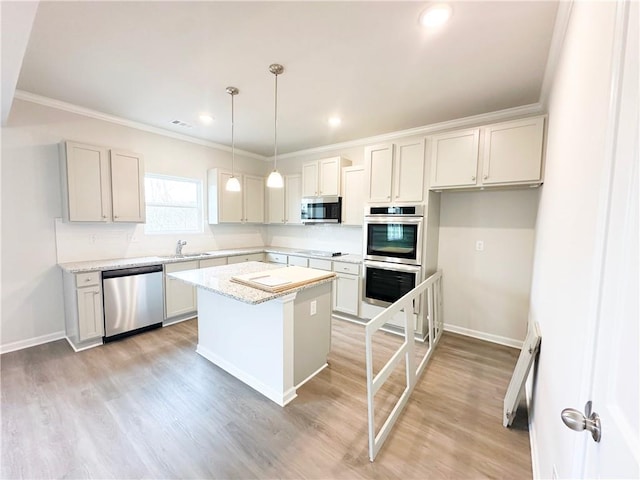 kitchen with light wood-style flooring, appliances with stainless steel finishes, a center island, and crown molding