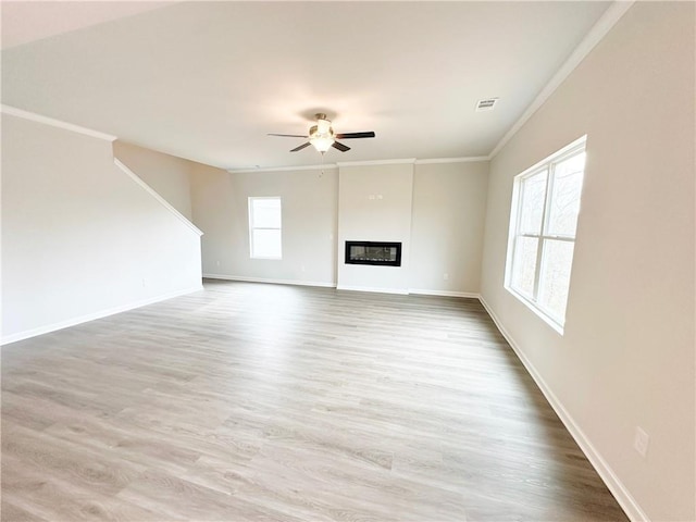 unfurnished living room featuring visible vents, crown molding, ceiling fan, wood finished floors, and a glass covered fireplace