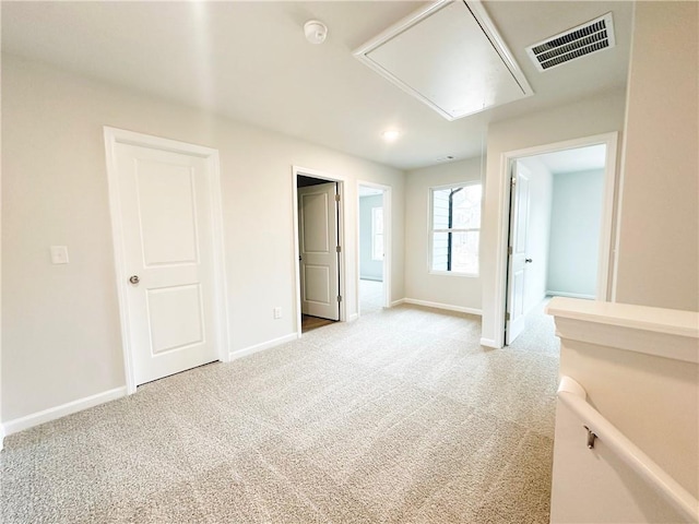 unfurnished bedroom with visible vents, light colored carpet, attic access, and baseboards