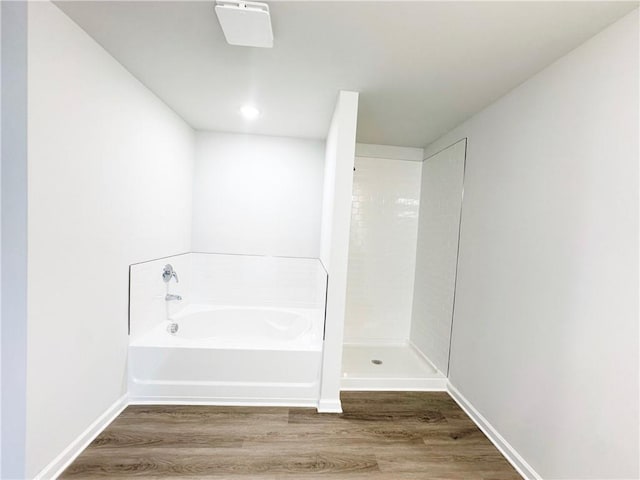 bathroom with baseboards, a shower, a garden tub, and wood finished floors