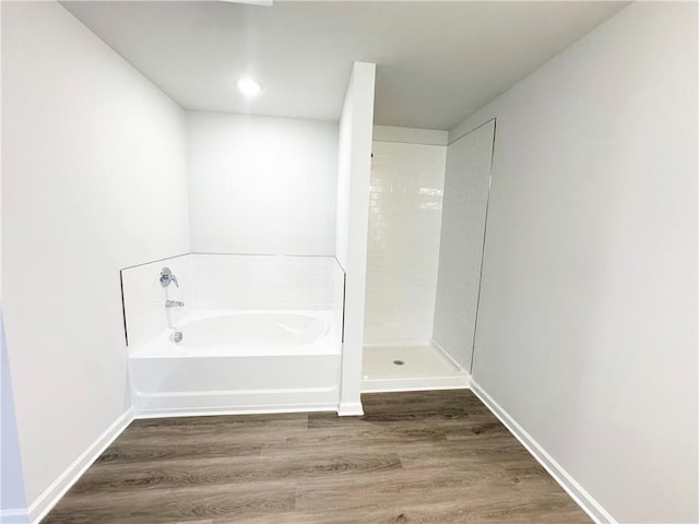 bathroom featuring a garden tub, wood finished floors, and baseboards