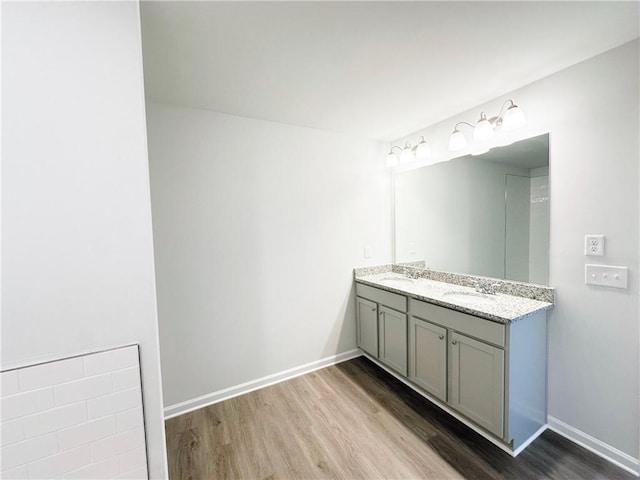 bathroom featuring double vanity, a sink, baseboards, and wood finished floors