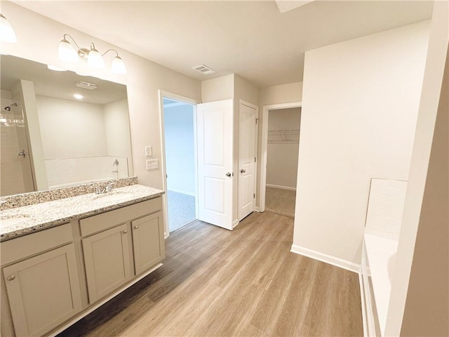 bathroom featuring wood finished floors, visible vents, a tile shower, a sink, and a bathtub