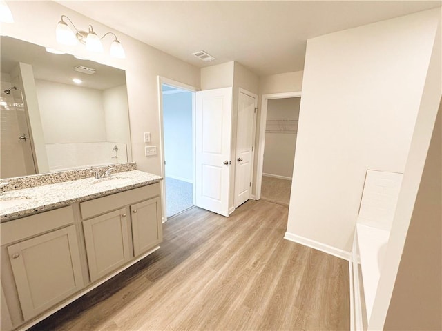 full bathroom with wood finished floors, visible vents, a bathtub, and a sink