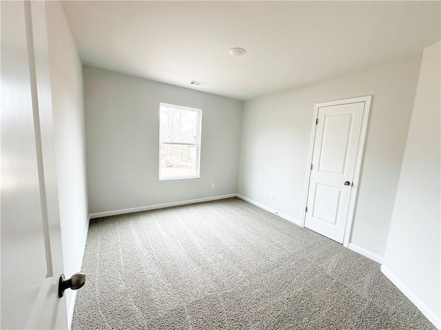 carpeted spare room with visible vents and baseboards