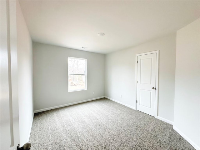 empty room featuring carpet flooring, visible vents, and baseboards