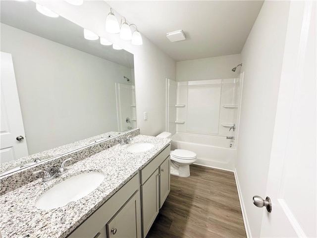 full bathroom featuring double vanity, wood finished floors, toilet, and a sink