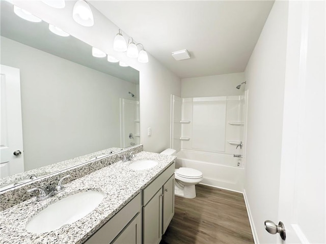 full bath with bathtub / shower combination, toilet, wood finished floors, and a sink