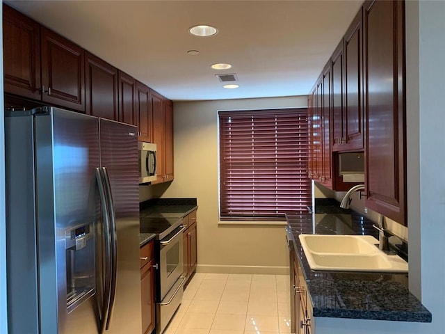 kitchen with light tile patterned flooring, appliances with stainless steel finishes, sink, and dark stone countertops