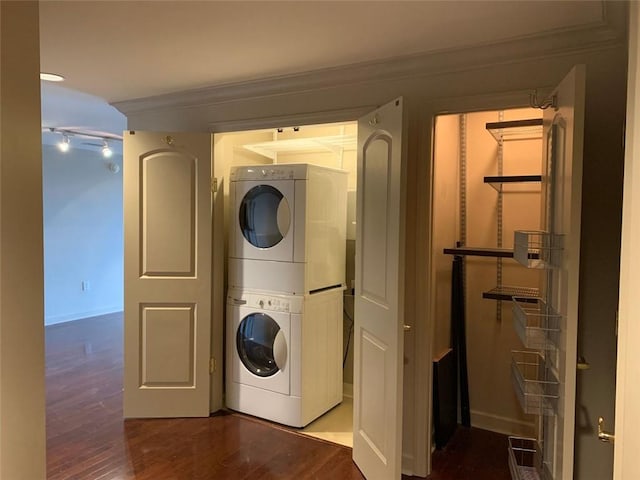 laundry area with stacked washer and clothes dryer, ornamental molding, and dark wood-type flooring