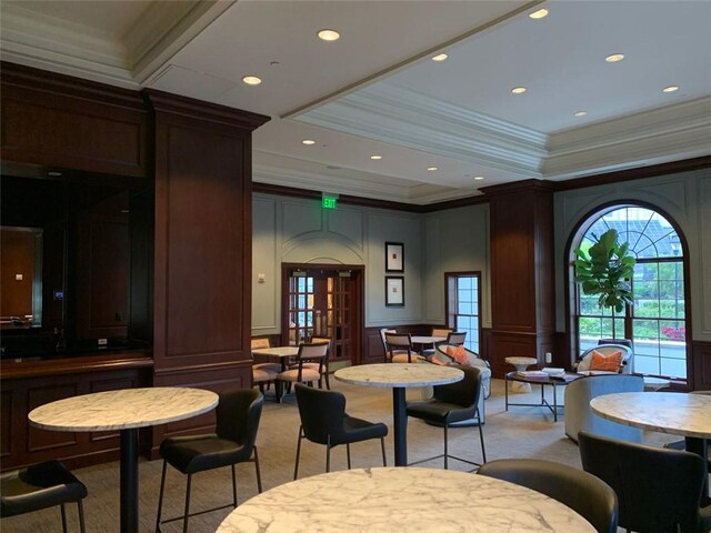 dining space with crown molding, light colored carpet, and decorative columns