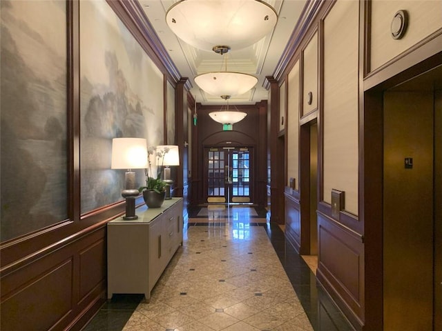 hallway featuring a raised ceiling, ornamental molding, french doors, and elevator