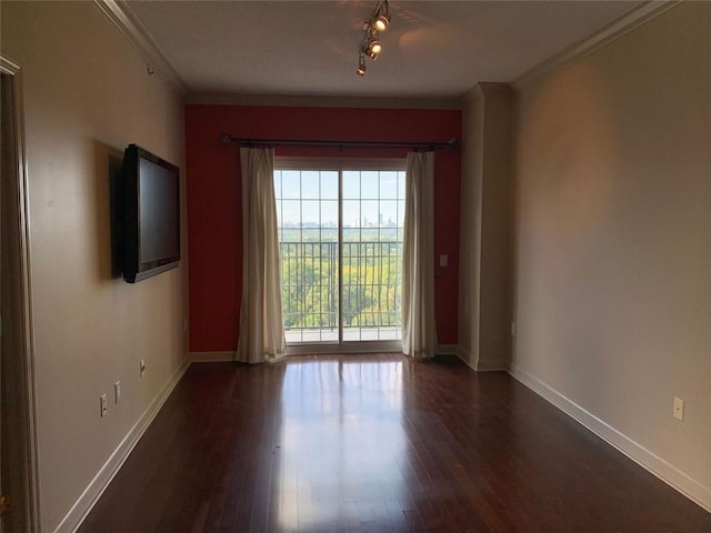 unfurnished room with dark hardwood / wood-style flooring, track lighting, and ornamental molding