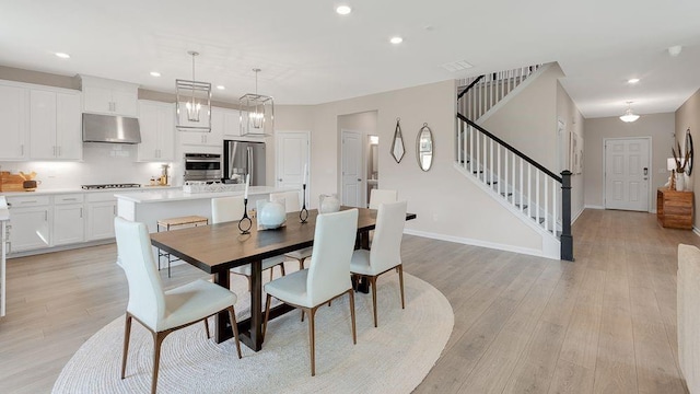 dining space with light wood-type flooring, recessed lighting, baseboards, and stairs