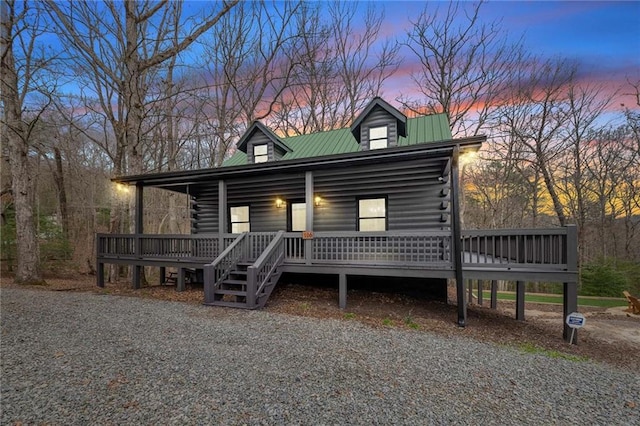 view of front facade featuring covered porch, log exterior, and metal roof