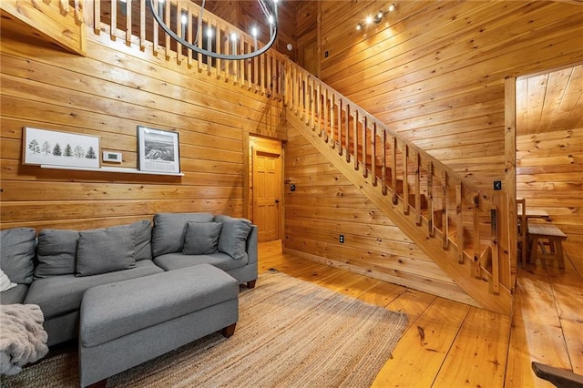 living area featuring wooden walls, stairway, wood ceiling, and hardwood / wood-style flooring