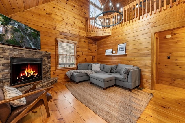 living room with a stone fireplace, wood-type flooring, a healthy amount of sunlight, and wood walls