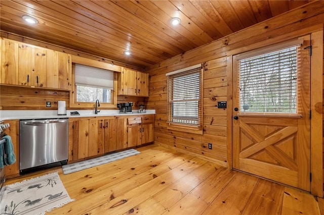 kitchen with wooden walls, a sink, light countertops, stainless steel dishwasher, and wooden ceiling
