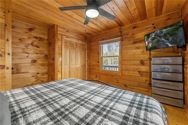 unfurnished bedroom featuring wooden walls, wood ceiling, wood finished floors, a closet, and a ceiling fan