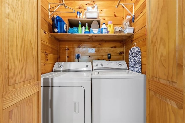 washroom featuring laundry area, wooden walls, and washer and clothes dryer
