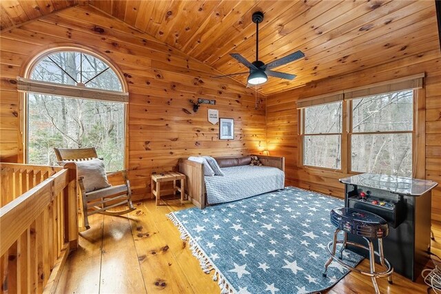 bedroom featuring ceiling fan, wood walls, wooden ceiling, and light wood-type flooring