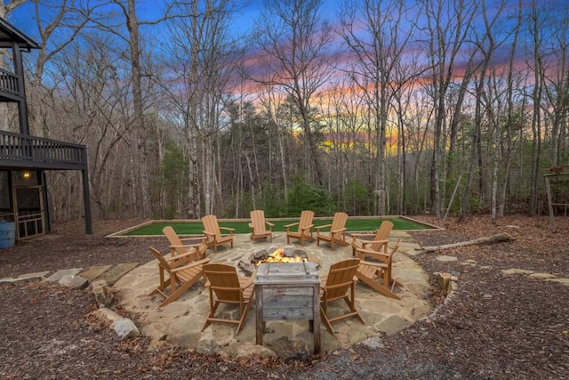 patio terrace at dusk featuring a wooden deck and a fire pit