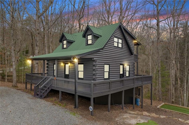 log home featuring log siding, covered porch, driveway, and metal roof