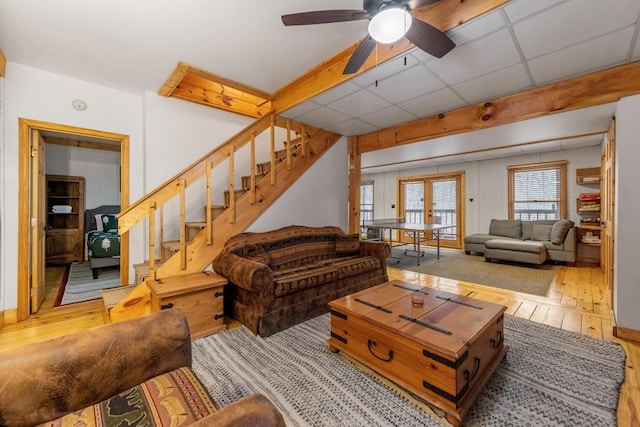 living room with a drop ceiling, light hardwood / wood-style floors, french doors, and ceiling fan