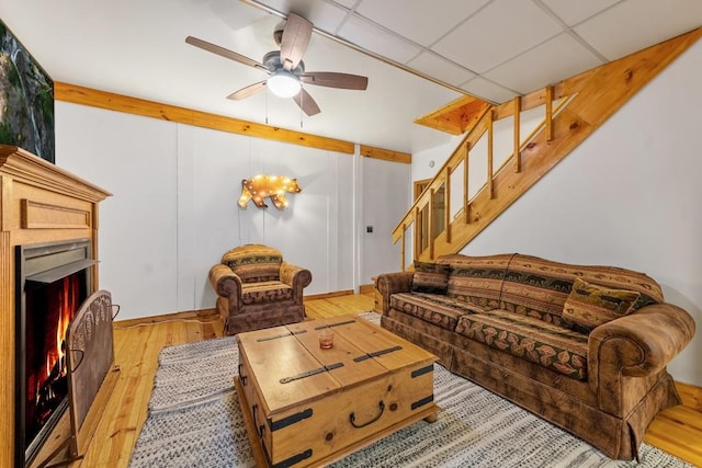 living room featuring a drop ceiling, ceiling fan with notable chandelier, and light hardwood / wood-style floors